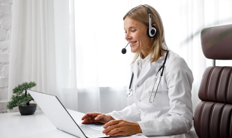 Doctor smiling in front of a laptop wearing headset
