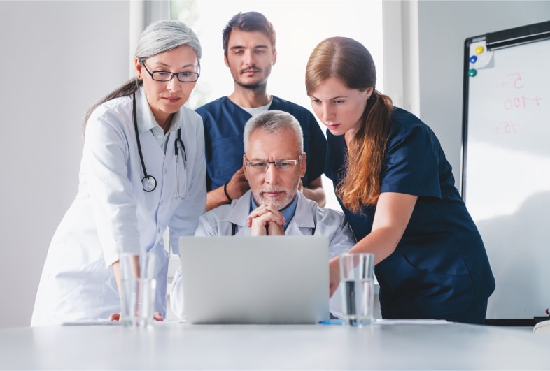 Group of doctors discussing in front of a laptop