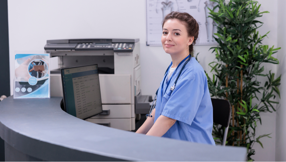 Nurse standing on nurse station in front of a computer